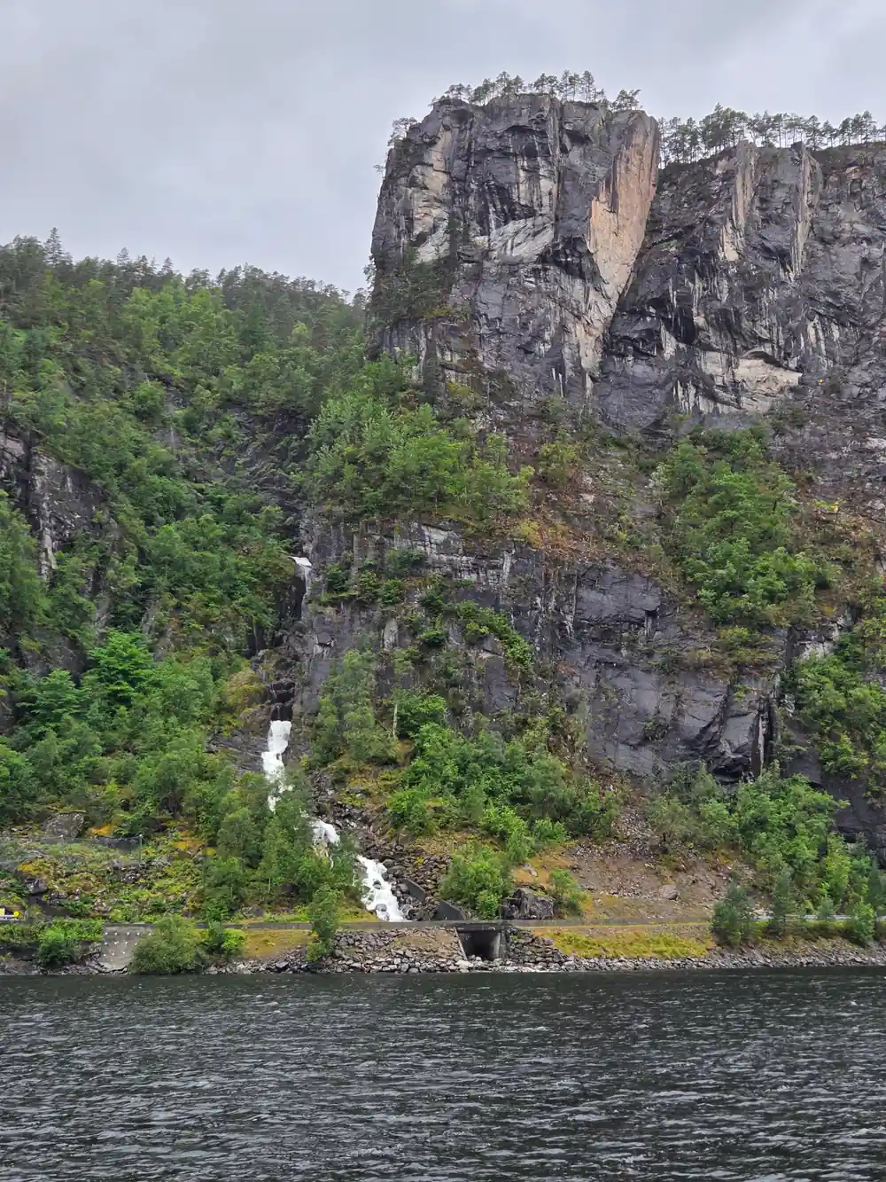 A cliff face with small falls running down to the water
