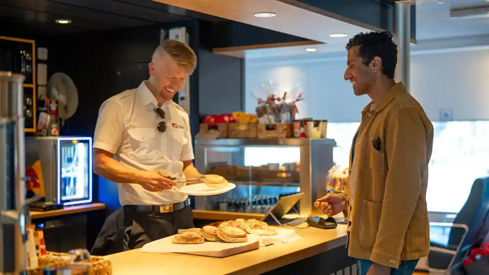 Crew serving pastries at the onboard kiosk
