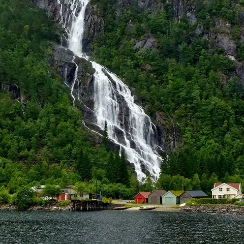 A tall waterfall dropping to the fjord