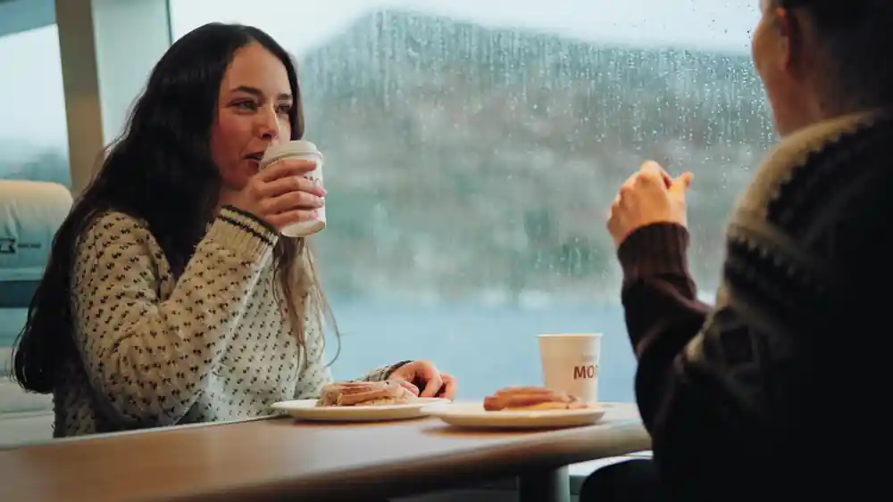 A guest with coffee and pastries at a window table