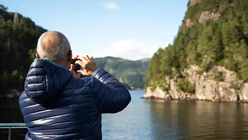 A guest photographing the fjord from the deck