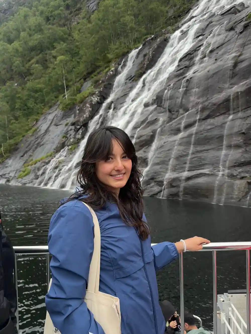 A guest at the rail with a waterfall behind her
