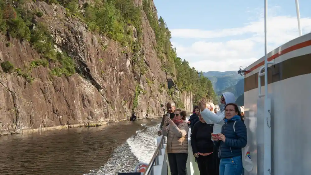 Guests at the rail photographing a cliff close alongside