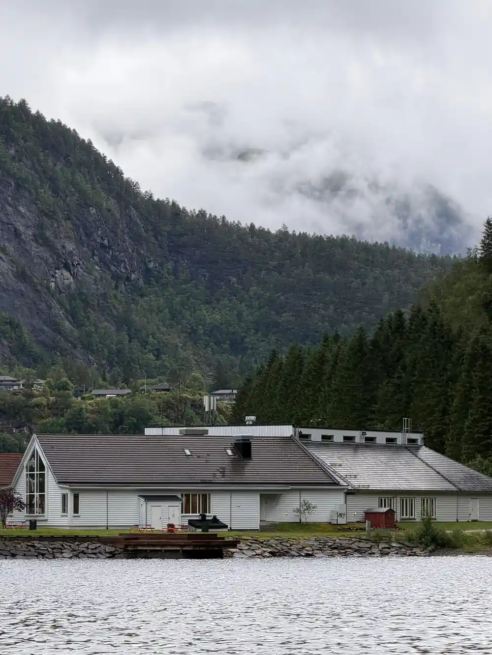 Low cloud sitting on the mountains above a shoreline house