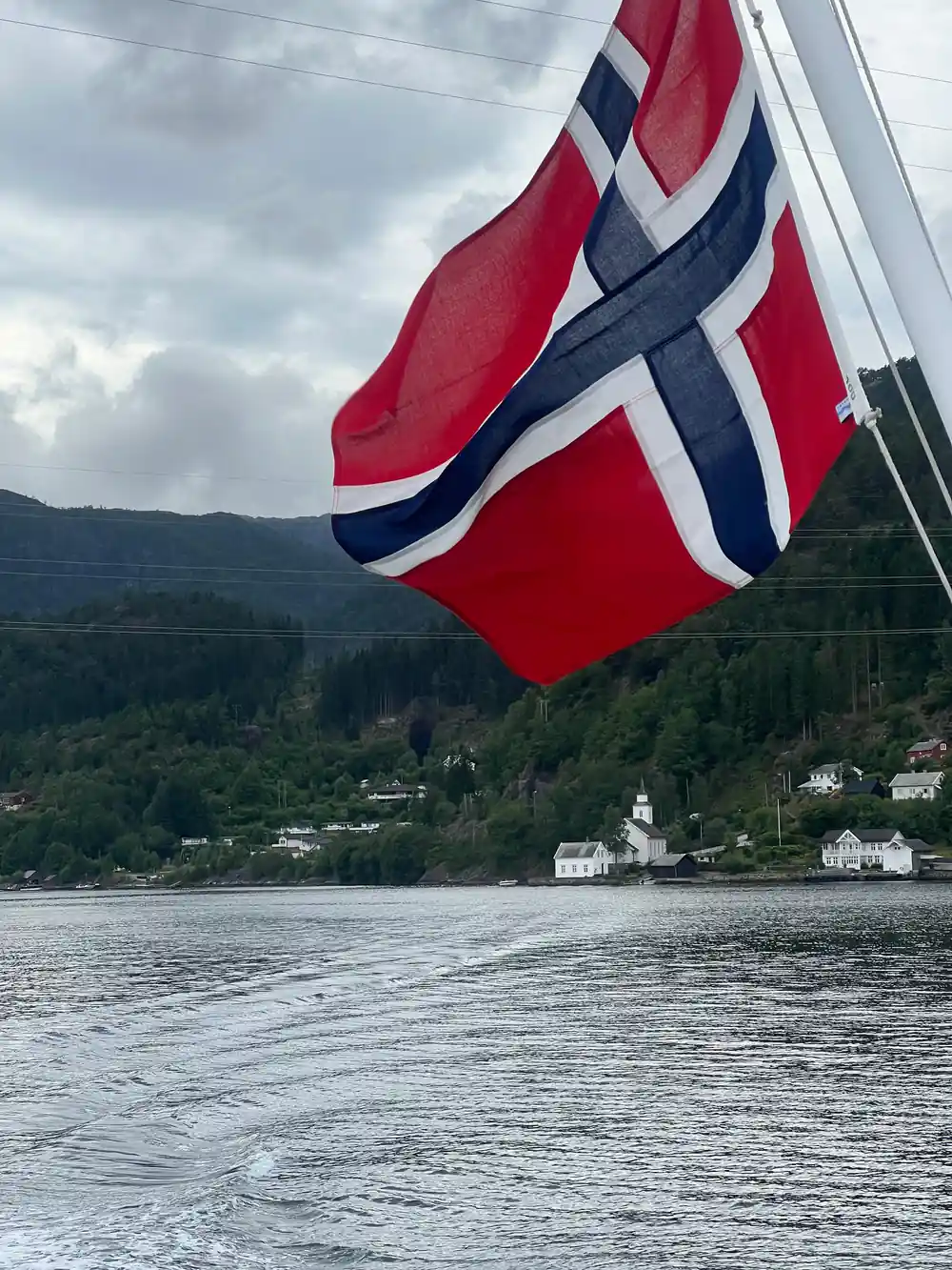The Norwegian flag flying above the fjord shoreline