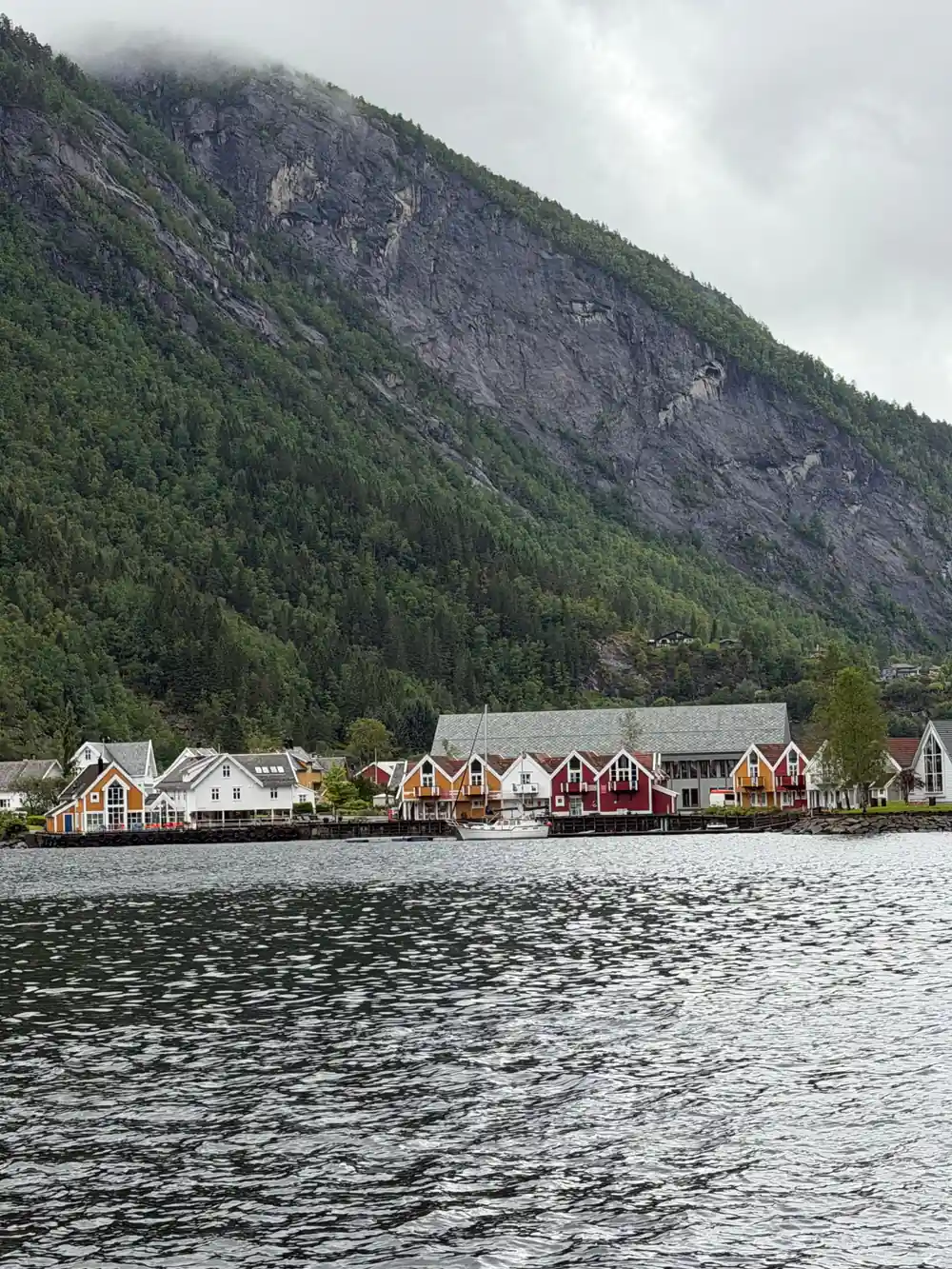Painted houses at the water beneath a steep green mountain