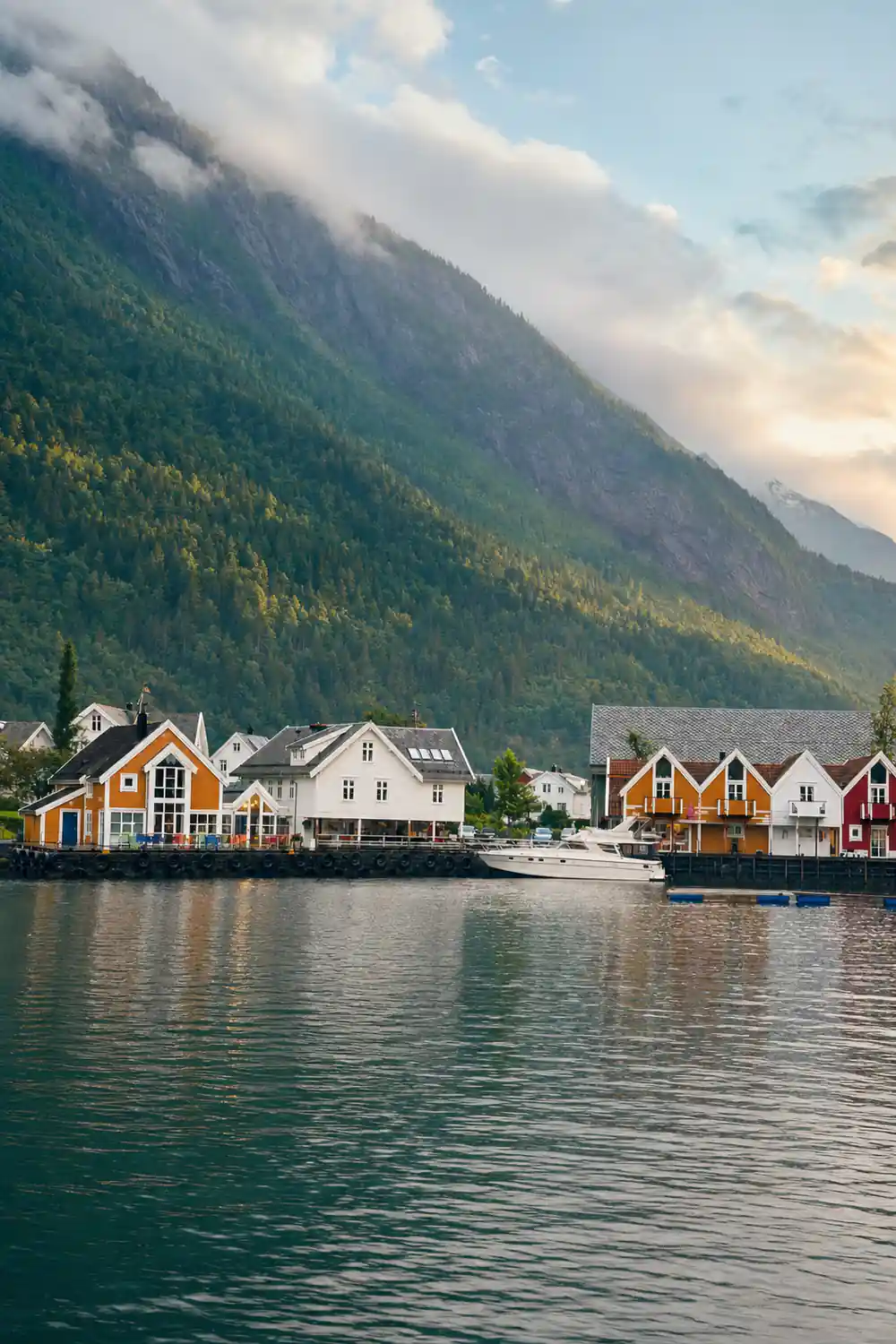 A shoreline village with a moored boat below the mountains