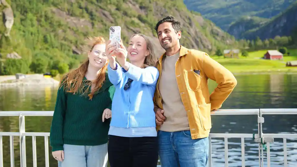 Three guests taking a photograph together on deck
