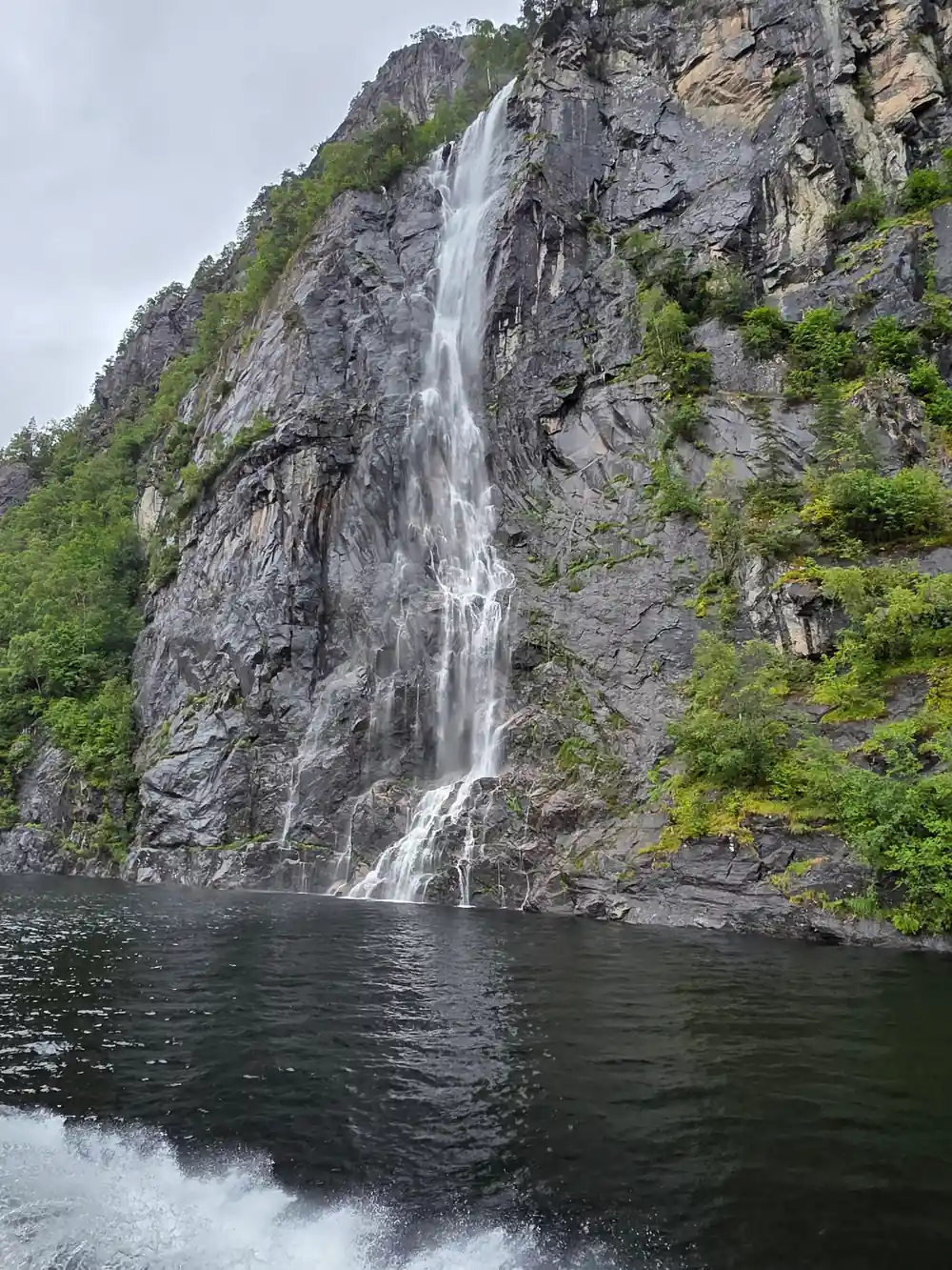 A waterfall dropping straight into the fjord from a cliff