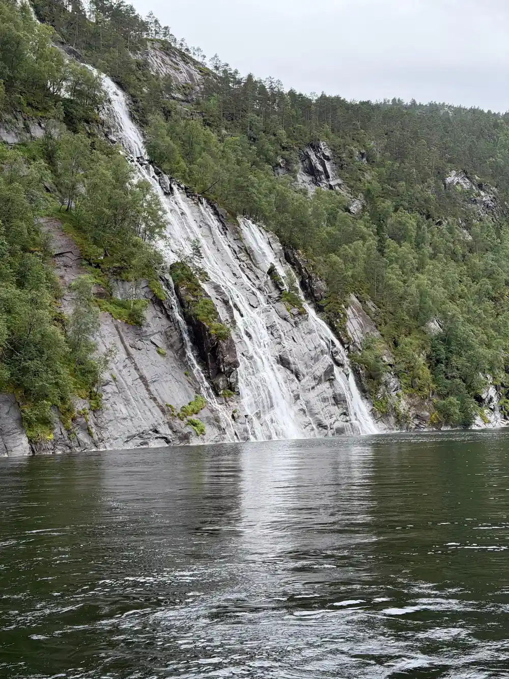 A waterfall meeting the fjord at the foot of a cliff