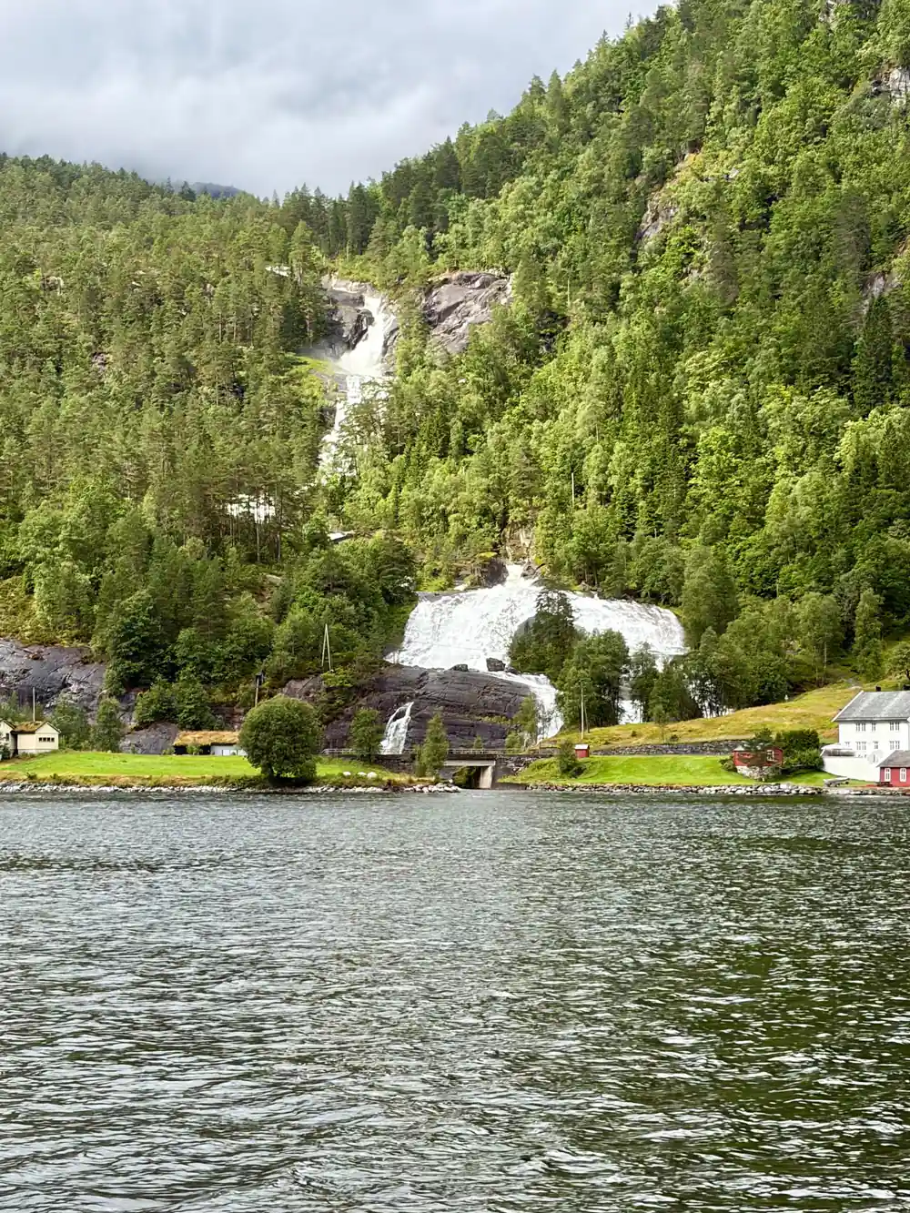 A waterfall reaching the fjord beside a small settlement