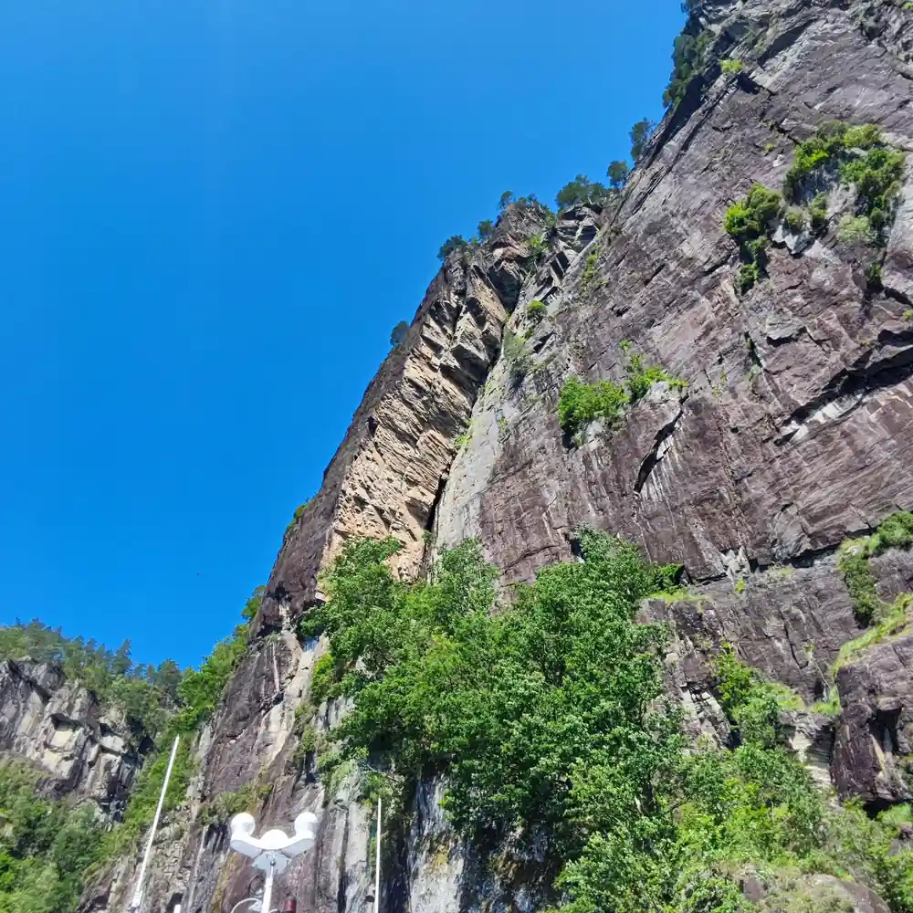 A waterfall running down a huge grey cliff under blue sky